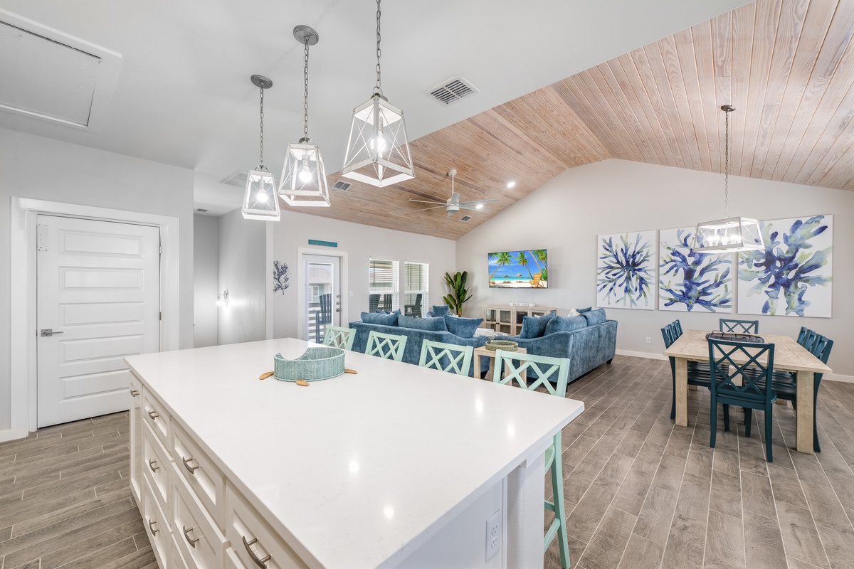 Unwind in your spacious open-plan living area featuring coastal-inspired decor, modern kitchen island, and cozy seating perfect for memorable gatherings.