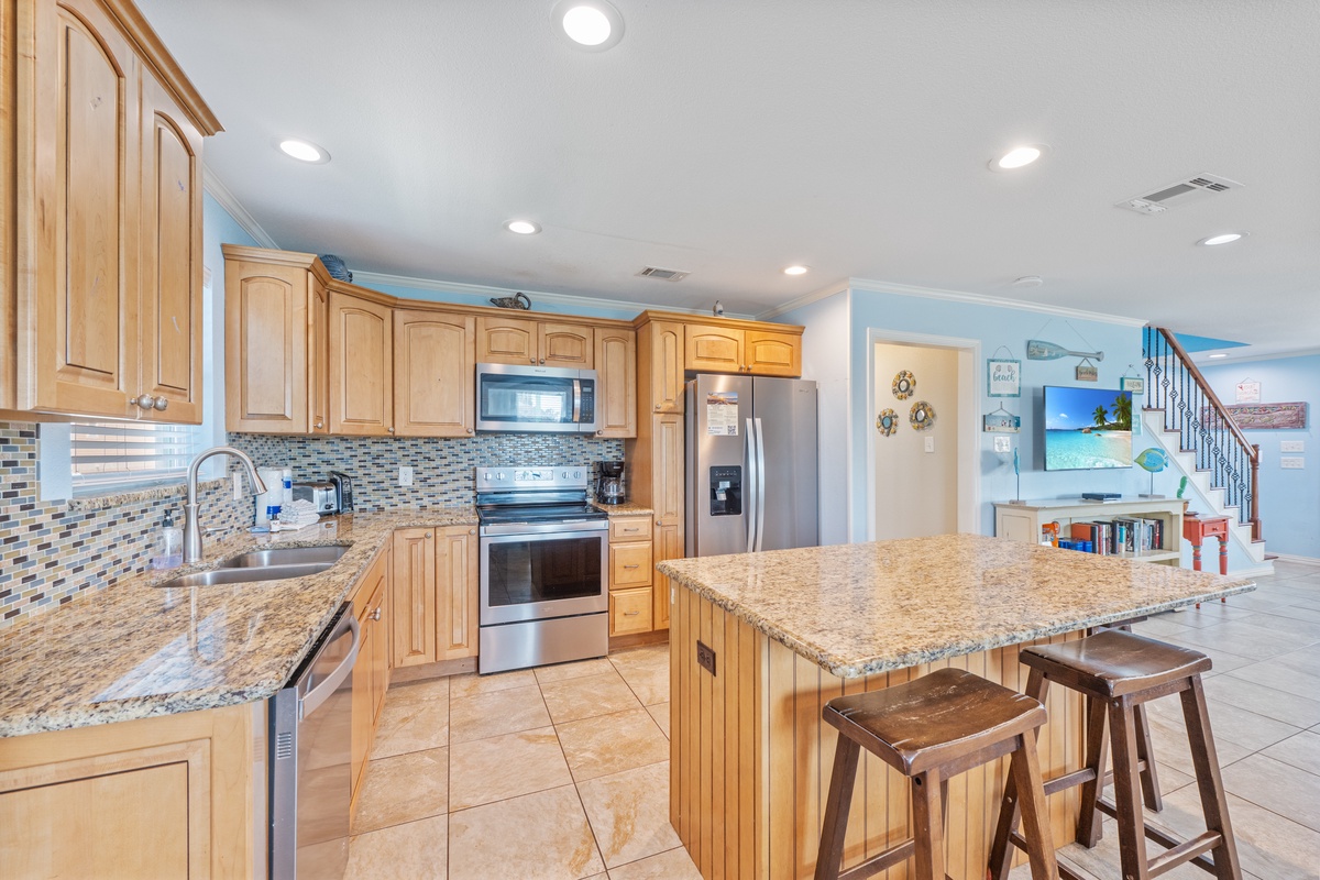 Your fully equipped kitchen awaits with granite counters, stainless appliances, and a breakfast bar perfect for morning coffee or casual meals.