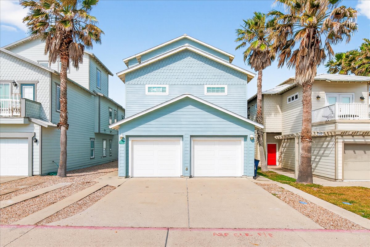 Charming coastal beach house with tropical palm trees and convenient garage parking in a vibrant neighborhood setting.