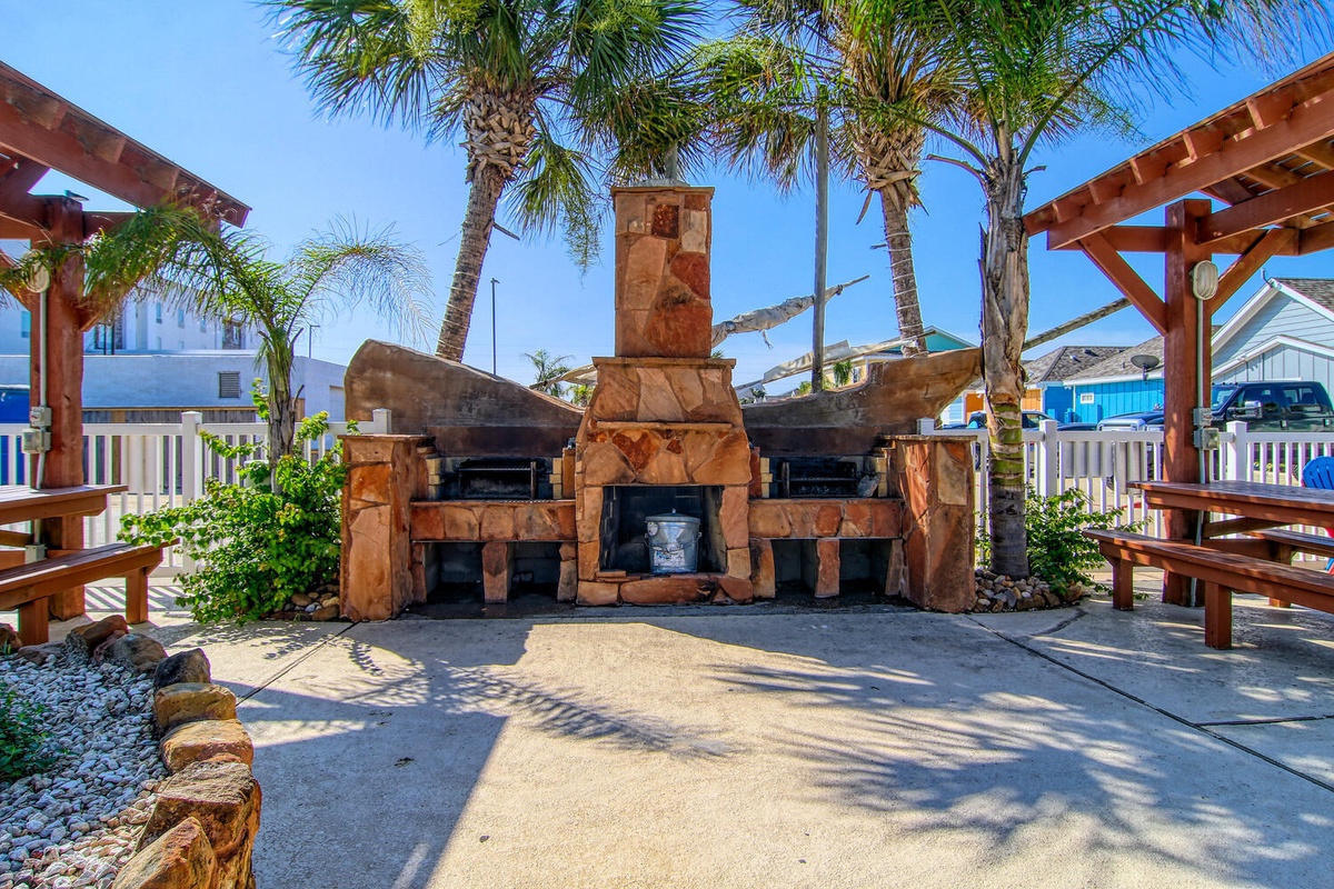 Gather around this stunning outdoor stone fireplace with BBQ facilities, perfectly framed by swaying palm trees for memorable evenings.