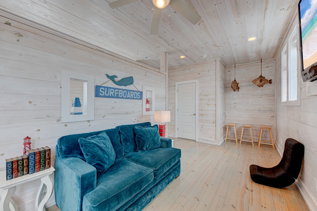 Sink into the plush teal sofa surrounded by coastal charm and natural wood warmth in this inviting beach-themed living space.