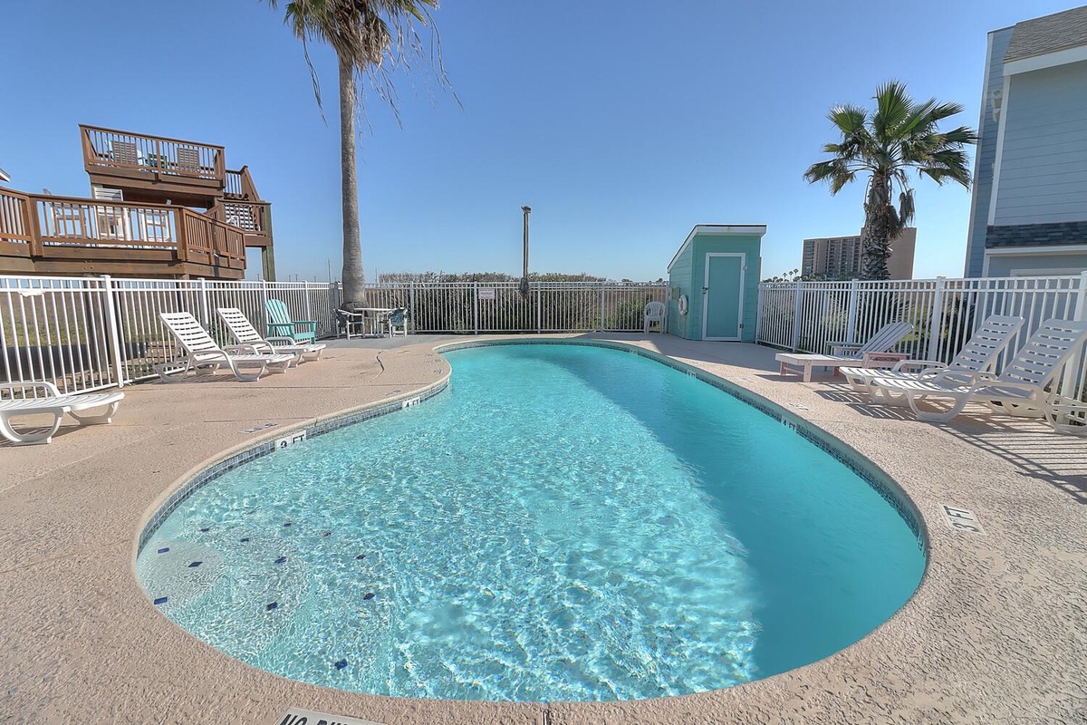Dive into crystal-clear waters surrounded by swaying palms and comfortable lounge chairs for your perfect poolside retreat.