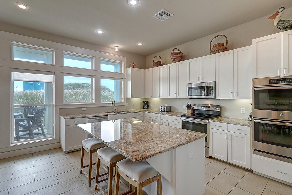 Your dream kitchen awaits with granite counters, stainless appliances, and stunning views of sand dunes beyond the windows.