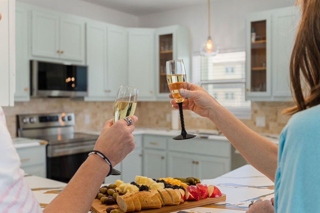 Raise your glass in the elegant white kitchen, where golden light and marble counters create the perfect setting for intimate celebrations.