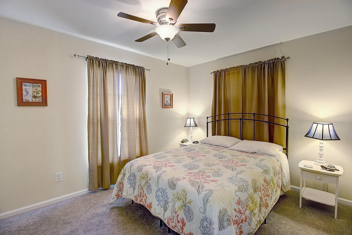Unwind in your peaceful bedroom with soft natural light, gentle ceiling fan, and cozy bedside lamps creating the perfect retreat.