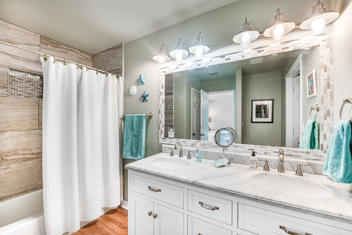 Refresh in your elegant bathroom with dual vanities, marble countertops, and a spa-like tiled shower with coastal touches.