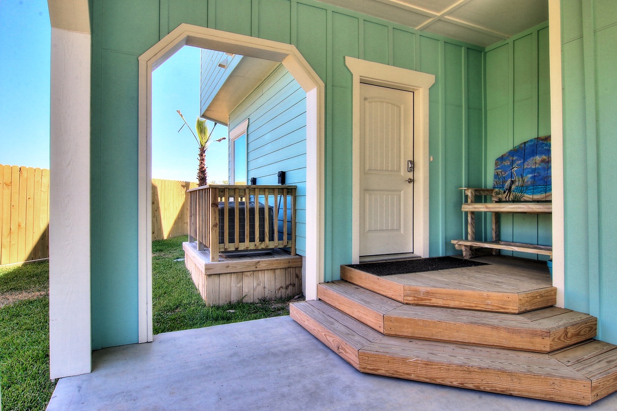 Charming turquoise beach cottage entrance with wooden steps leading to your private retreat, complete with coastal décor and nearby hot tub relaxation.