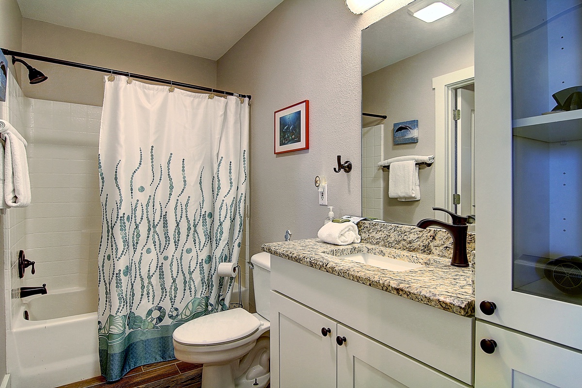 Refresh in your private bathroom featuring coastal-inspired touches, granite countertops, and ocean-themed artwork that brings beachy vibes indoors.