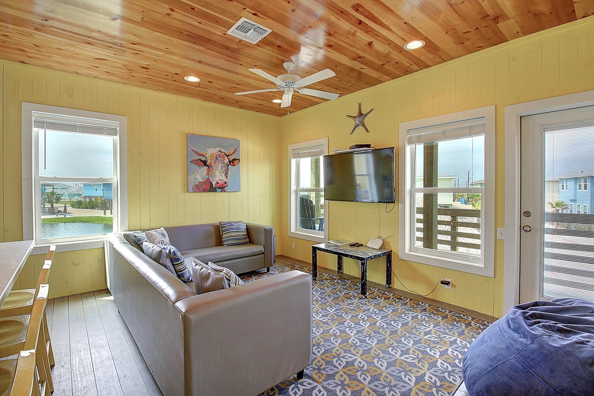 Relax in your bright living room with leather seating, entertainment center, and charming rustic ceiling—your cozy retreat awaits.