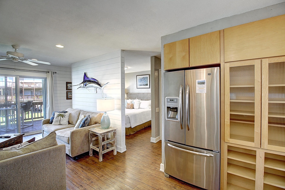 Your open-concept living space flows seamlessly from kitchen to bedroom, with warm wood floors and stainless appliances creating the perfect home base.
