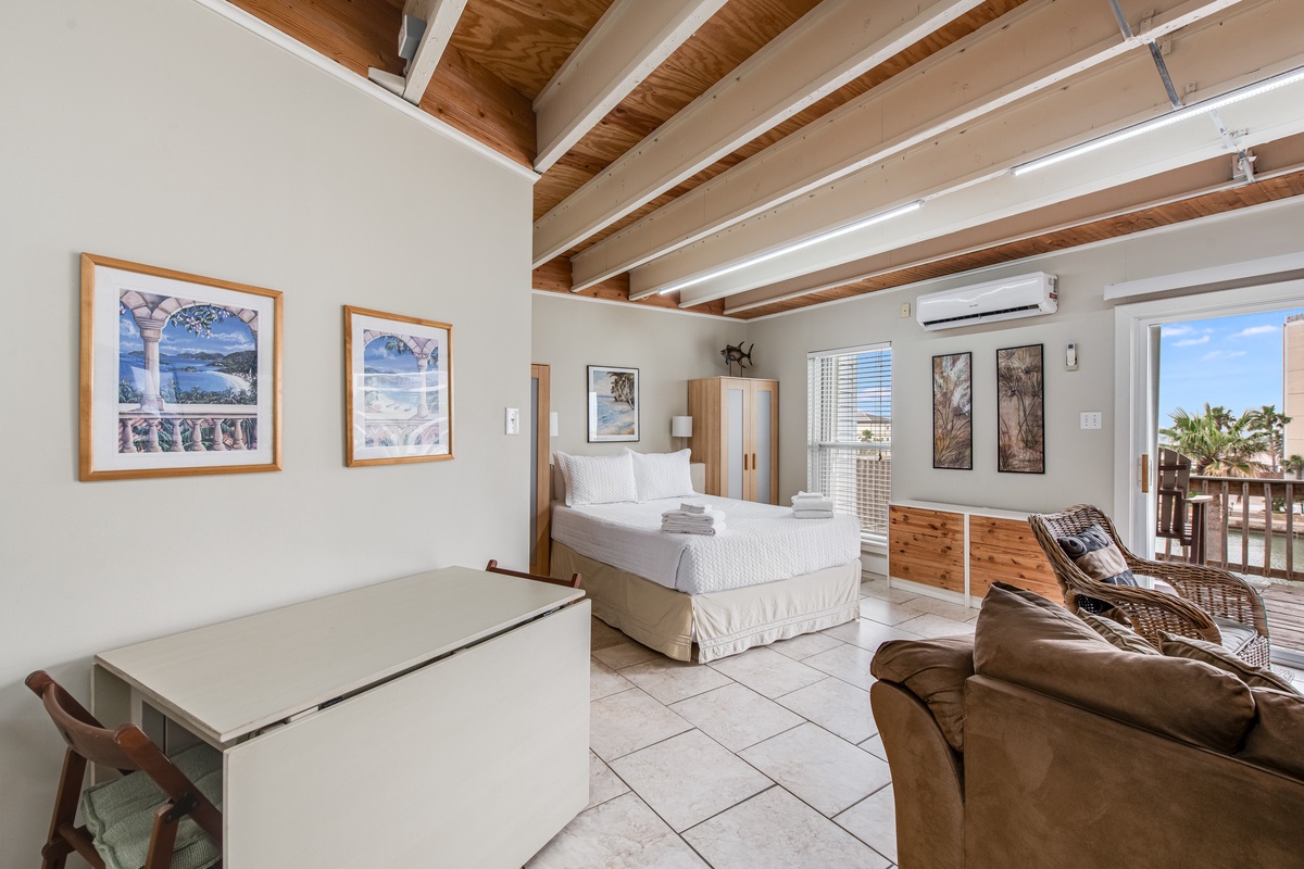 Unwind in your bright, airy studio with exposed wooden beams, comfortable seating, and tropical artwork adorning the walls.