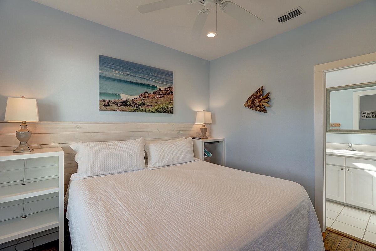Your coastal bedroom features soft blue walls, white linens, and ocean artwork to create a soothing seaside retreat.