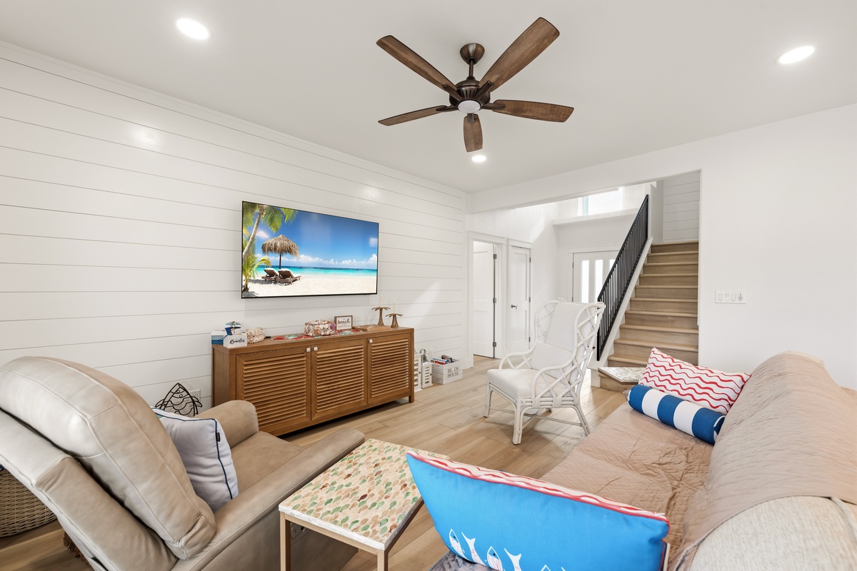 Sink into plush seating in your bright, airy living room, where coastal charm meets modern comfort under the gentle whirl of ceiling fans.
