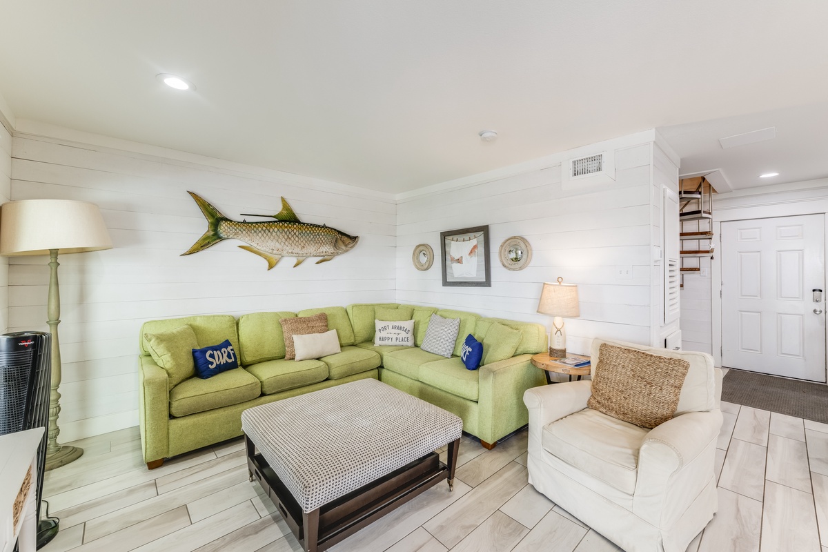 Settle into this bright, coastal living space with comfy seating and beachy décor. The cheerful green sectional and cozy chair invite you to unwind after a day of exploring.