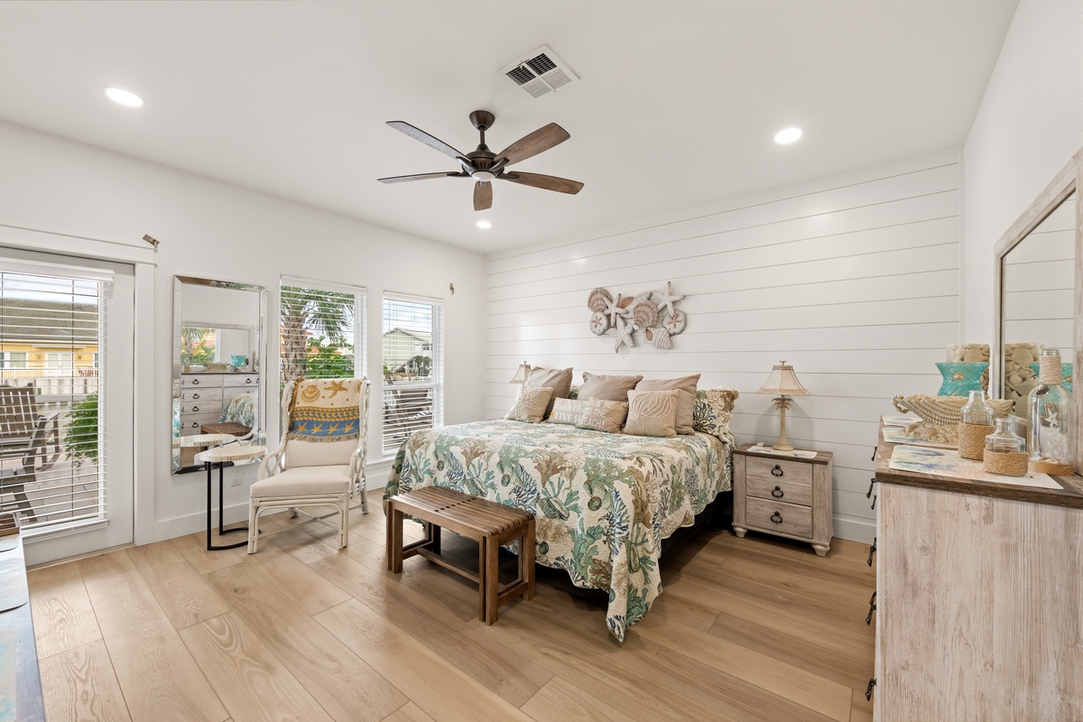 Drift off to coastal dreams in your serene bedroom, where shiplap walls and ocean-inspired décor create a beach house escape. Let the ceiling fan keep you cool as natural light pours in.