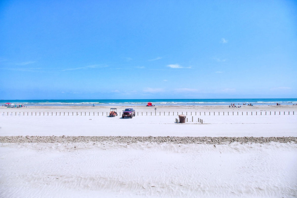 Pristine white sand beach stretches endlessly along turquoise waters, with colorful beach amenities and gentle waves creating the perfect coastal escape.