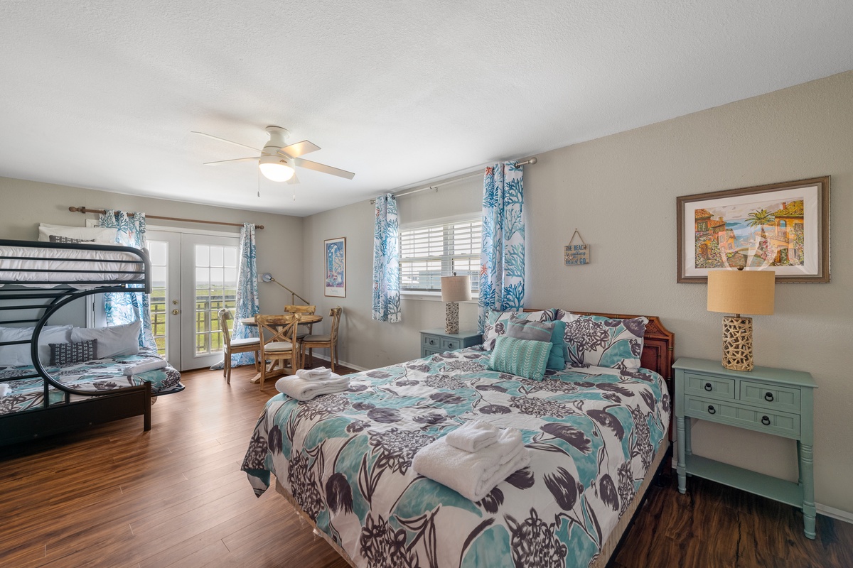 Drift off in your cheerful coastal bedroom, where a plush bed and cozy bunk setup welcome families, while ocean breezes and natural light stream through glass doors that lead to your own private balcony.