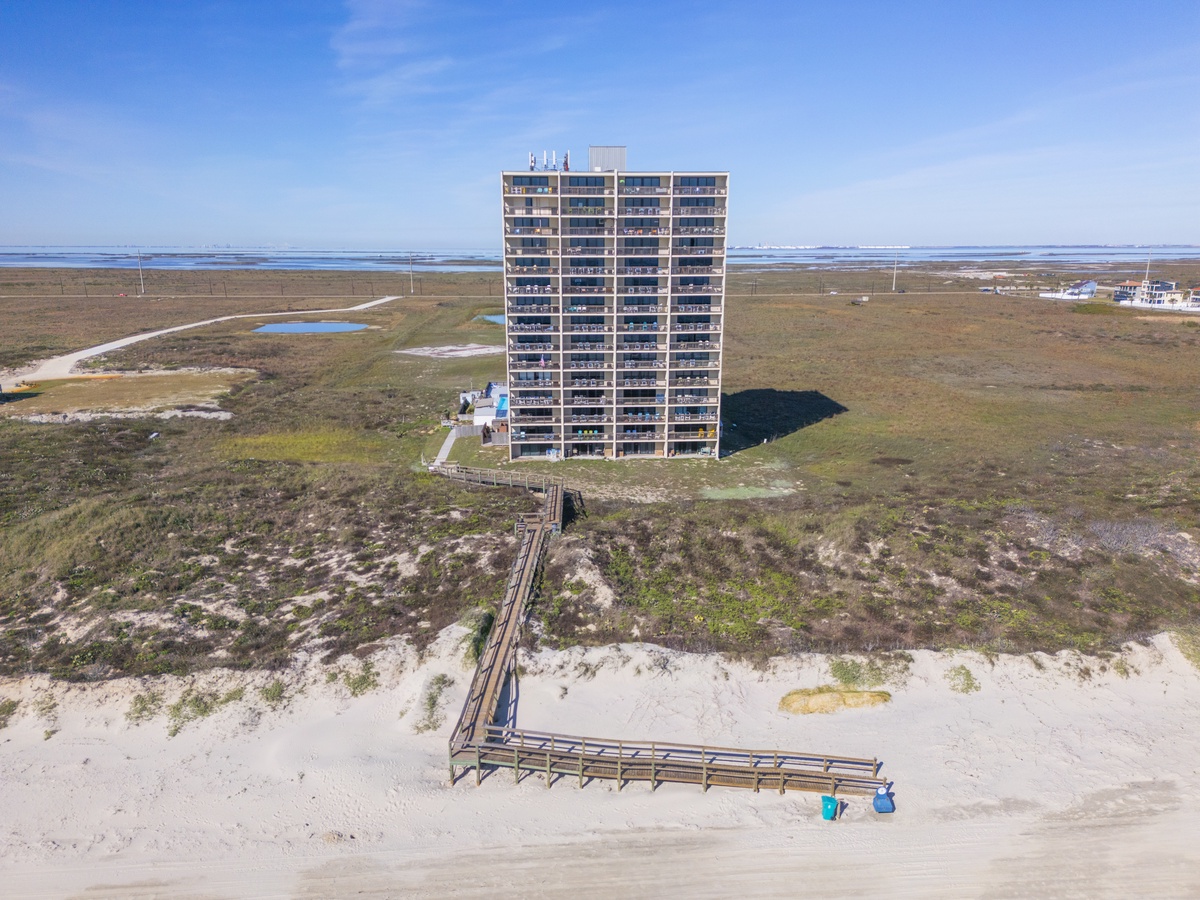 Oceanfront high-rise building positioned directly on the beach with boardwalk access and expansive coastal surroundings.