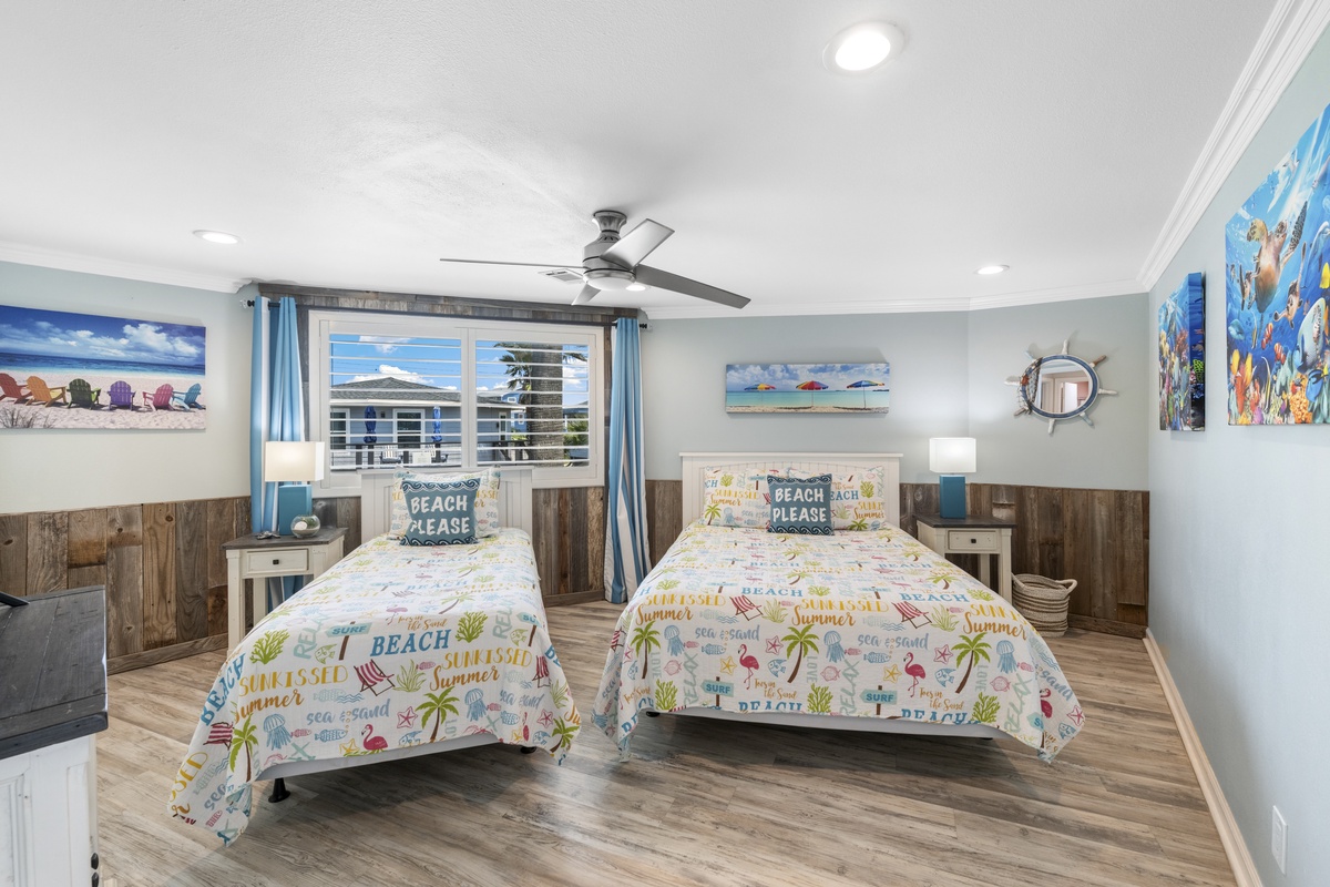 Your coastal bedroom features twin beds with cheerful beach-themed bedding and ocean artwork, perfect for sharing with family or friends.