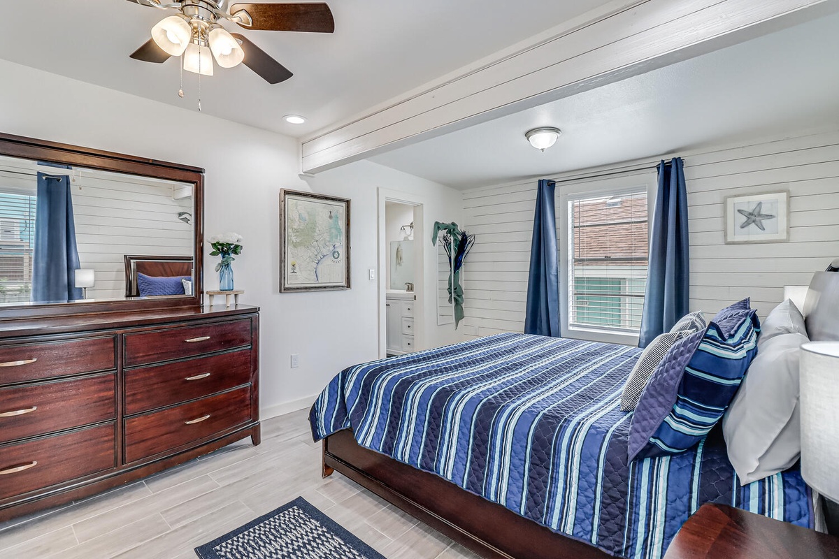 Your coastal bedroom retreat features crisp white shiplap walls, nautical blue accents, and rich wood furnishings for ultimate comfort.