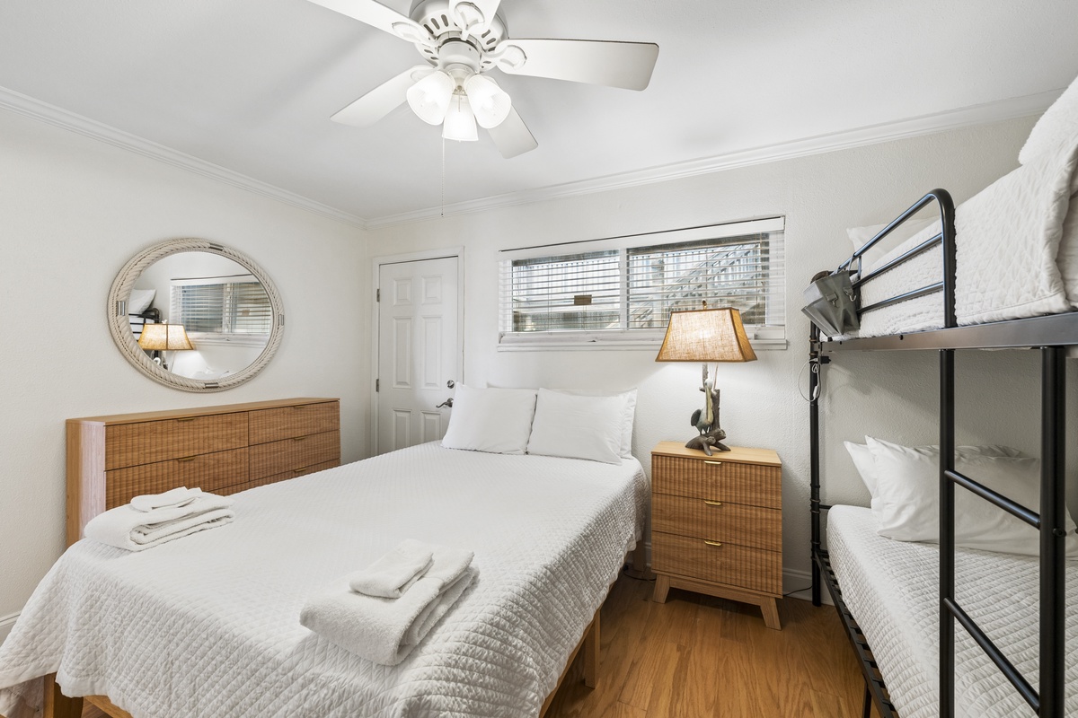 Slip into crisp white linens in your cozy bedroom, where warm wood accents and soft lighting create a peaceful retreat. The ceiling fan and large windows keep the space airy and bright.