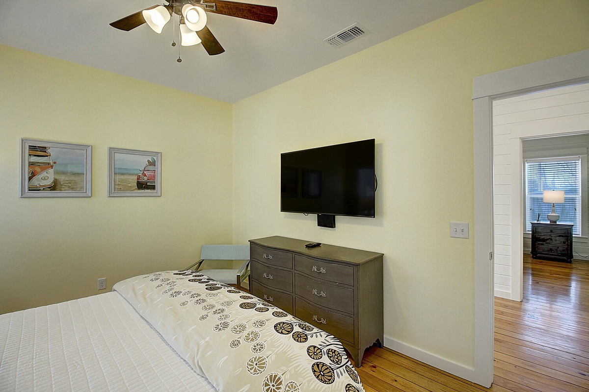 Unwind in your serene bedroom with a wall-mounted TV for evening entertainment and coastal artwork setting a peaceful mood.