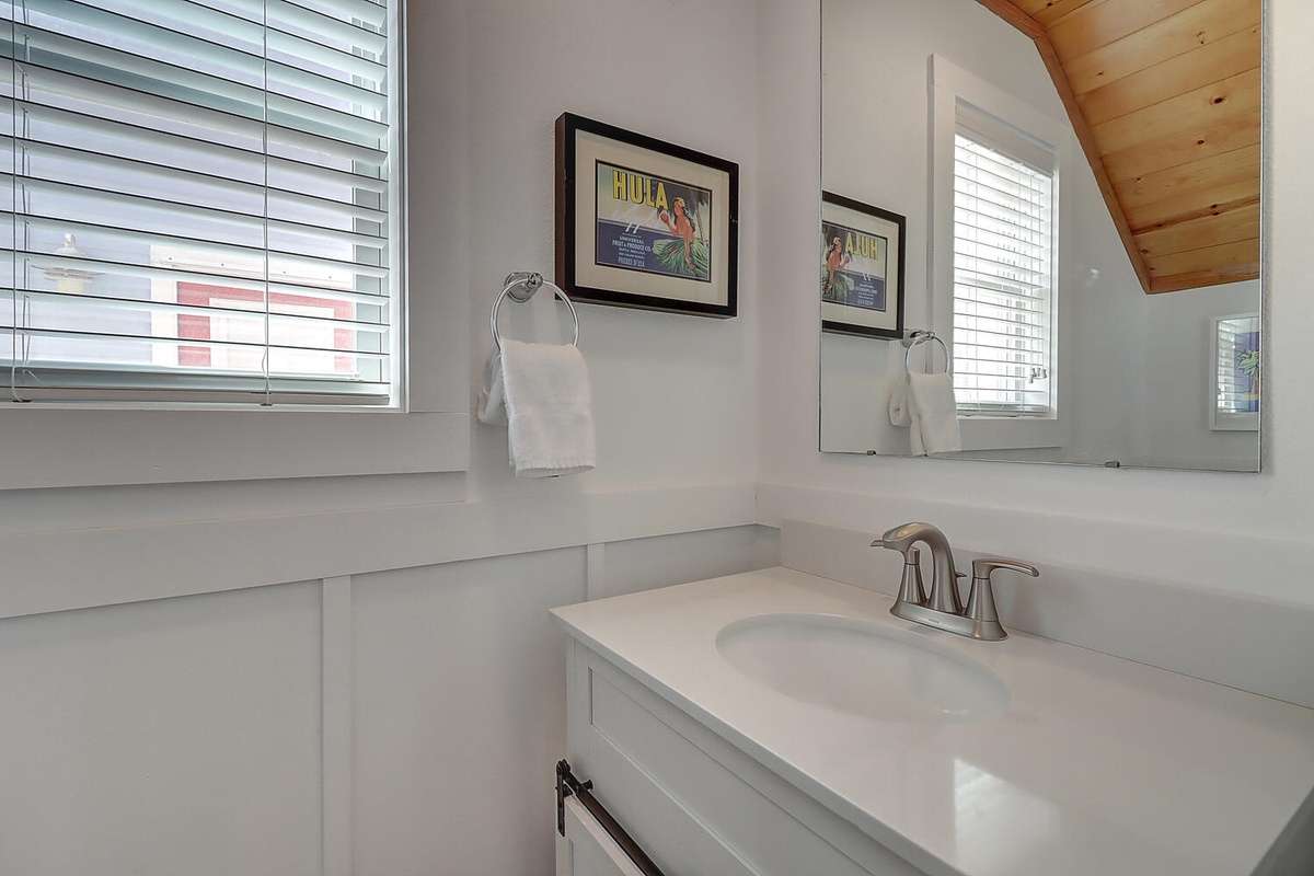 Start each day in your bright, pristine bathroom featuring a spacious vanity, fresh towels, and charming vintage artwork that adds personality to your morning routine.