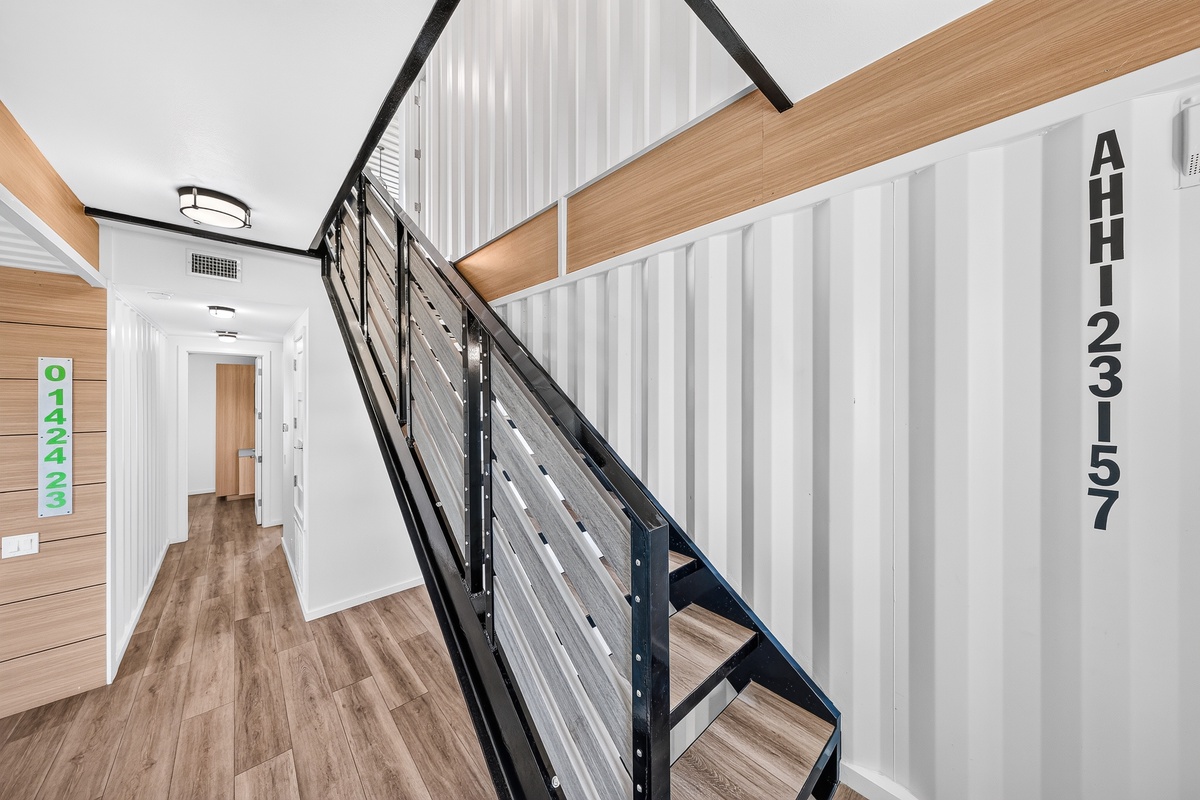Your rental features a modern staircase with sleek metal railings and warm wood flooring, combining industrial style with inviting textures.