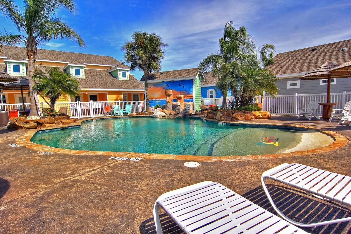 Dive into crystal-clear waters surrounded by tropical palms and colorful beach houses. Your perfect poolside retreat awaits with comfortable loungers and island vibes.