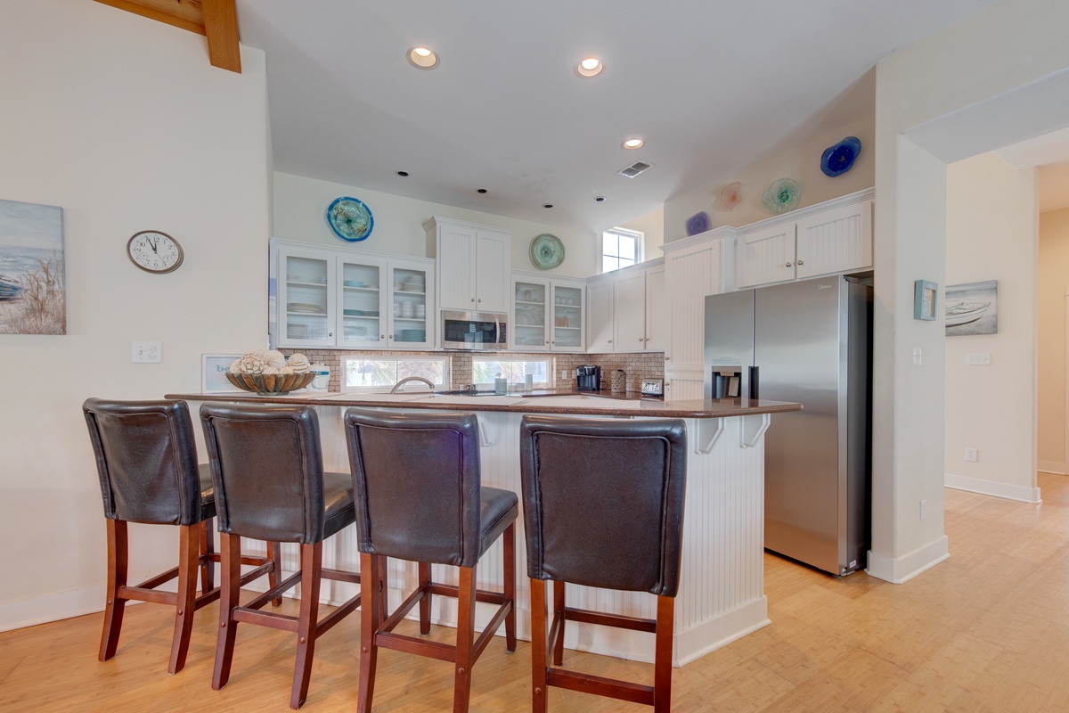 Your gourmet kitchen invites morning coffee at the breakfast bar, with coastal accents and gleaming appliances ready for culinary adventures.