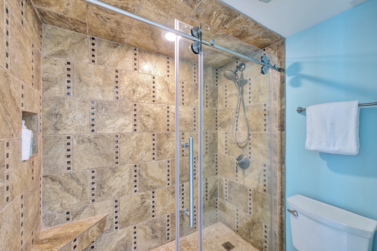 Step into your luxurious marble-tiled shower with glass doors and elegant blue walls for a spa-like retreat.