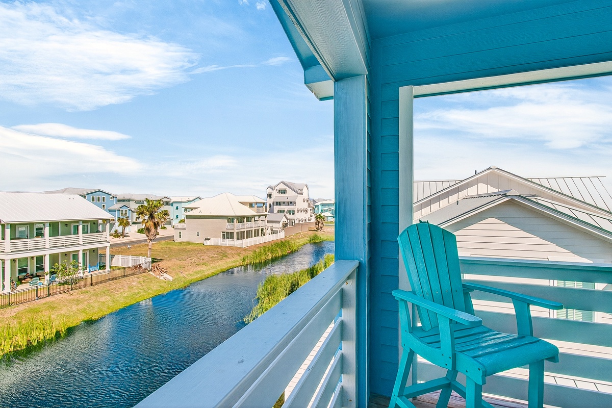 Relax in your turquoise Adirondack chair while enjoying serene canal views and coastal neighborhood charm from your private balcony.