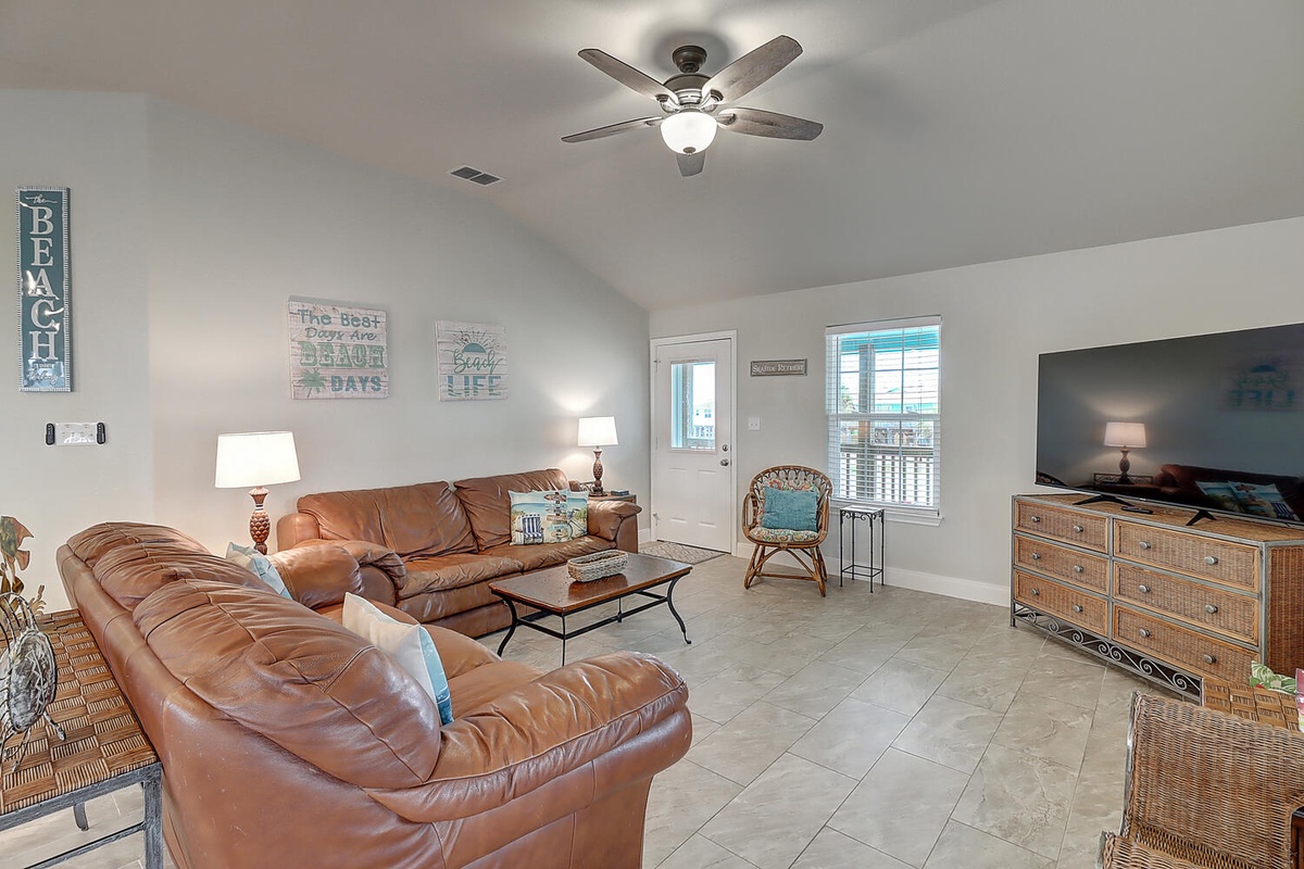 Sink into leather sofas while your ceiling fan keeps you cool in this bright, beach-themed living room perfect for relaxing.
