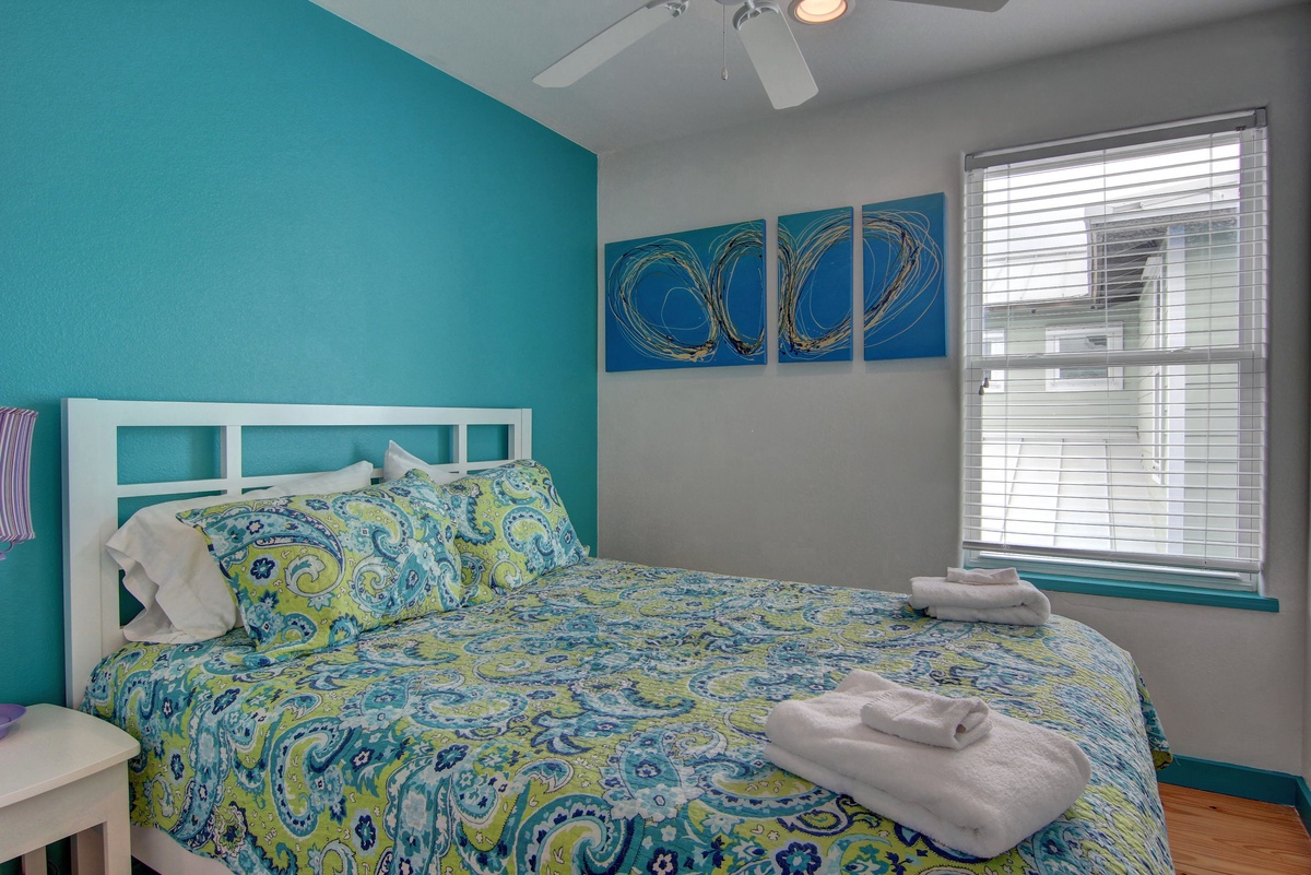 Drift off peacefully in your vibrant bedroom where fresh linens await and coastal artwork sets a tranquil mood for restful nights.