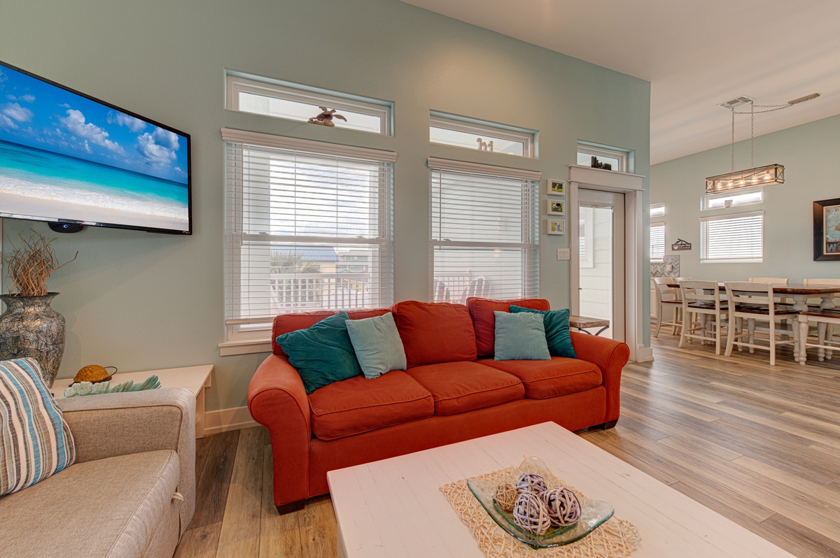 Relax in your spacious living room where vibrant coral furnishings meet coastal charm, perfect for unwinding after beach adventures.