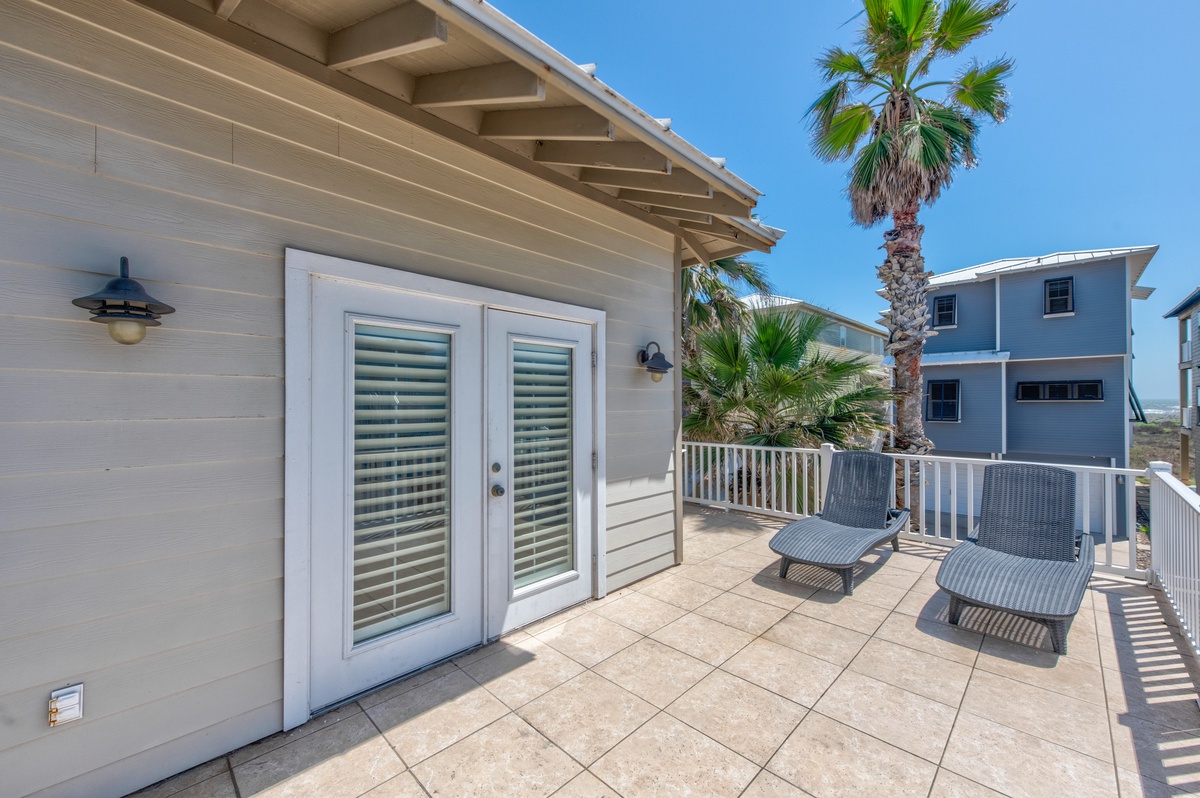 Spacious balcony with comfortable lounge chairs where you can relax under swaying palms and soak up the coastal sunshine.