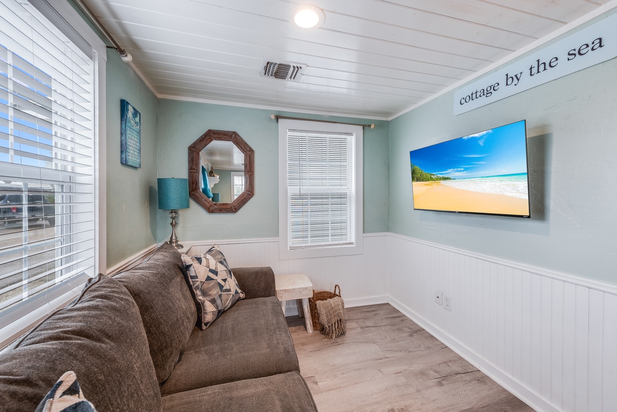 Unwind in your serene coastal retreat with soft turquoise walls, plush seating, and a wall-mounted TV for relaxing evenings.