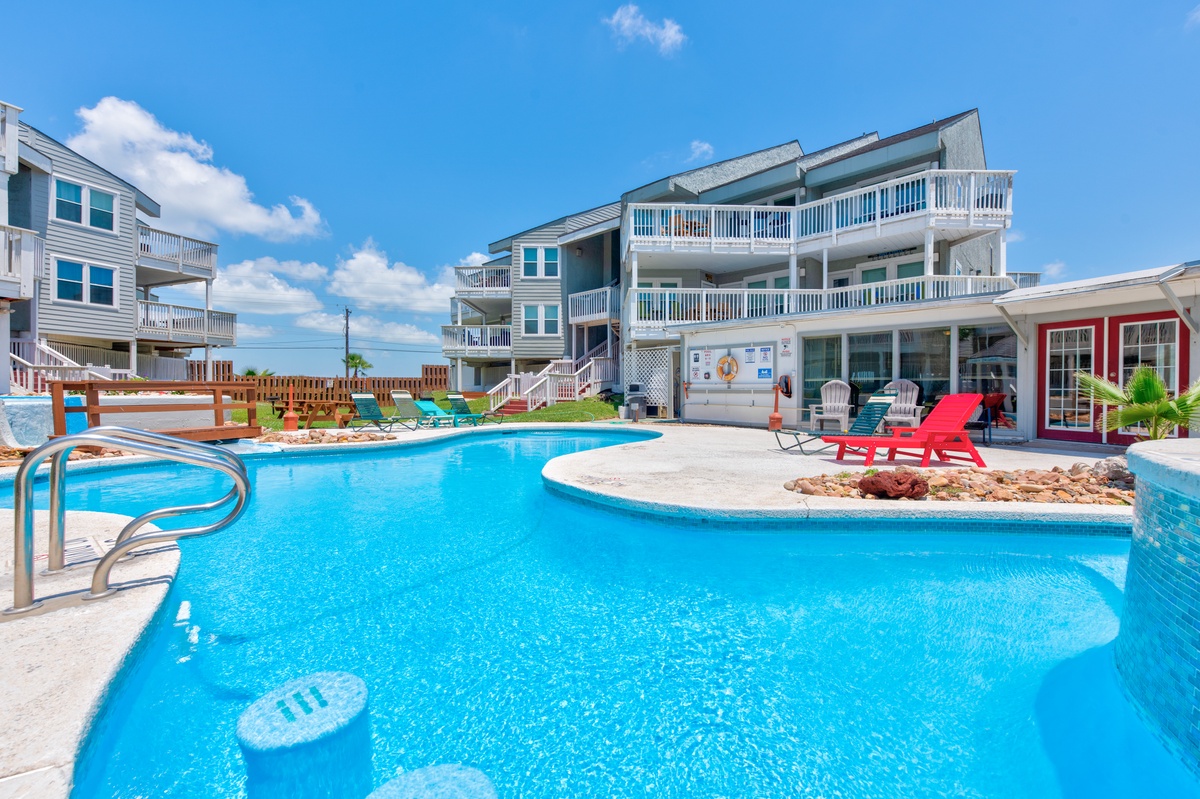 Dive into your private oasis with this stunning curved pool featuring crystal-clear waters and colorful lounge chairs for pure relaxation.
