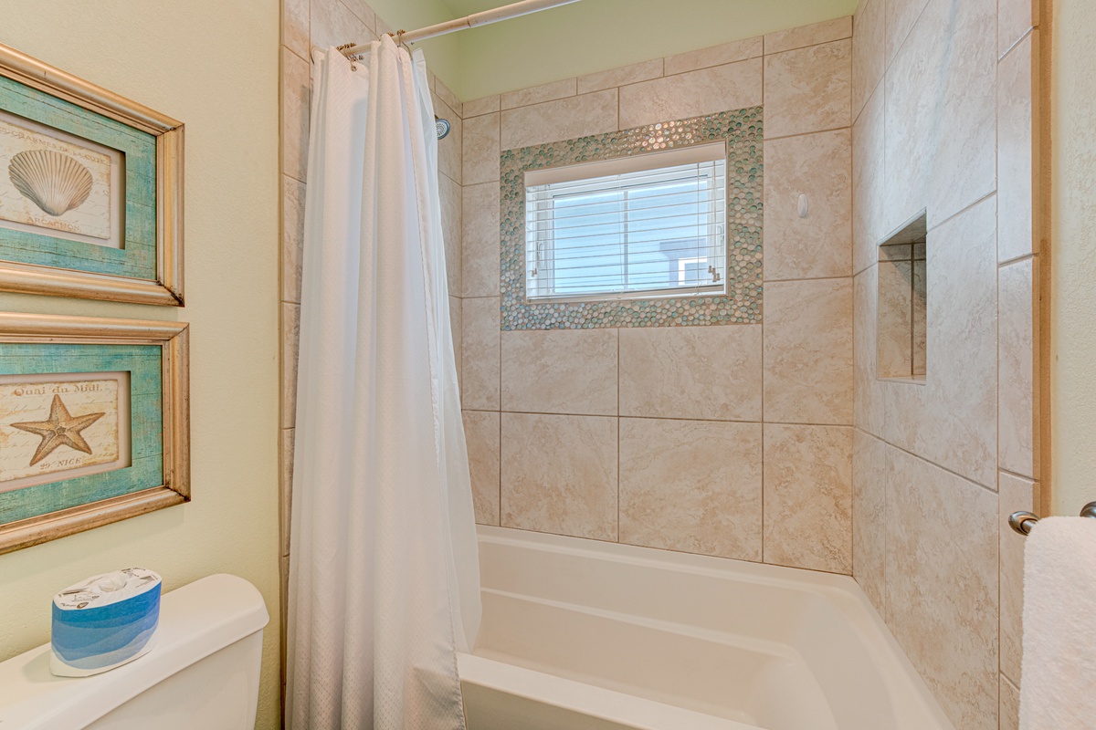 Refresh in your beautifully tiled bathroom with coastal touches, featuring a spacious tub-shower combo and charming seaside décor.