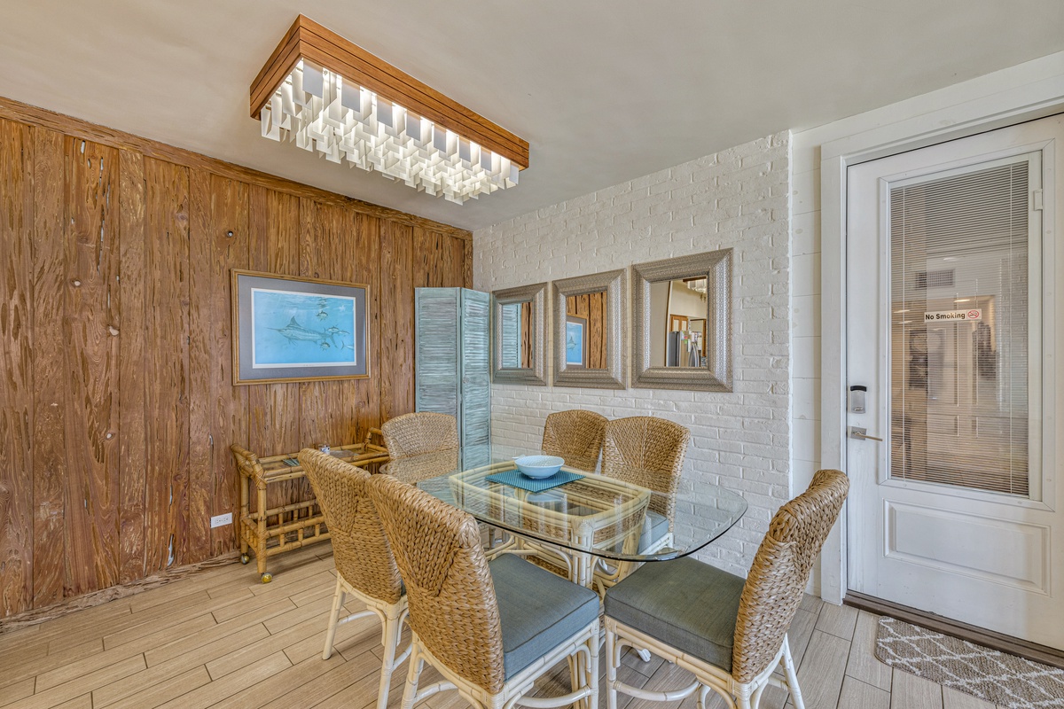 Your elegant dining space features wicker chairs around a glass table, where candlelit meals await beneath a stunning crystal chandelier.