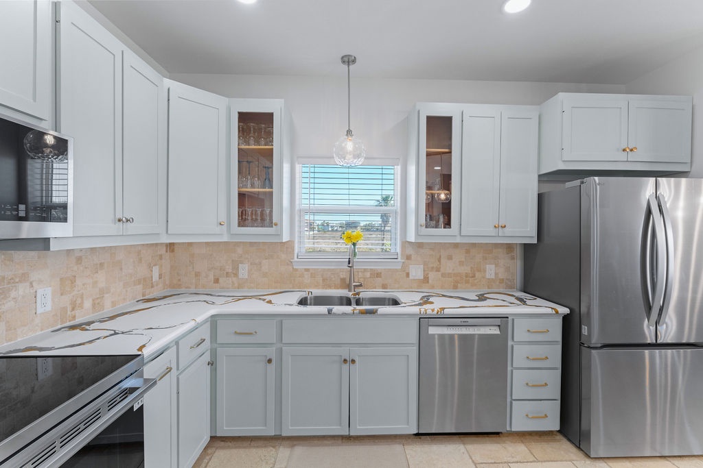 Your bright, fully equipped kitchen awaits with gleaming countertops, stainless steel appliances, and sunshine streaming through the window.