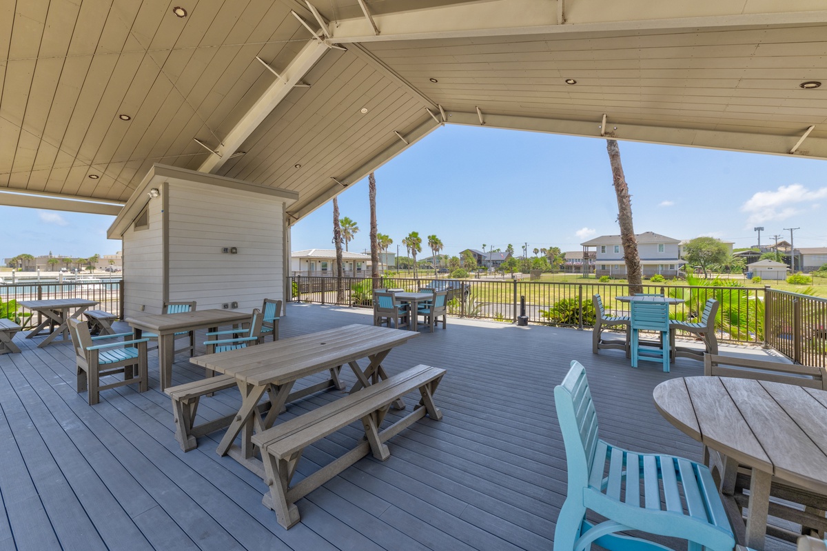 Your spacious covered deck offers multiple seating areas with picnic tables and colorful chairs, perfect for outdoor dining while enjoying tropical views.