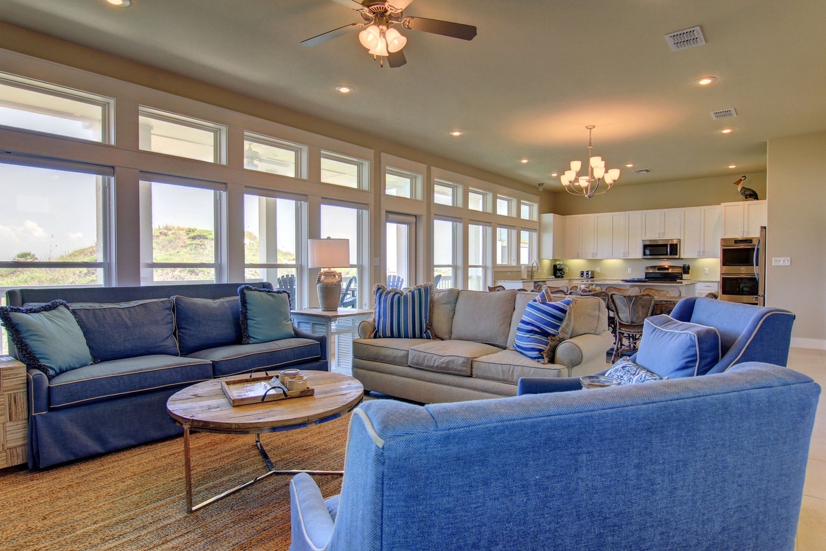 Relax in your spacious living room with plush blue seating and floor-to-ceiling windows that flood the space with natural light.