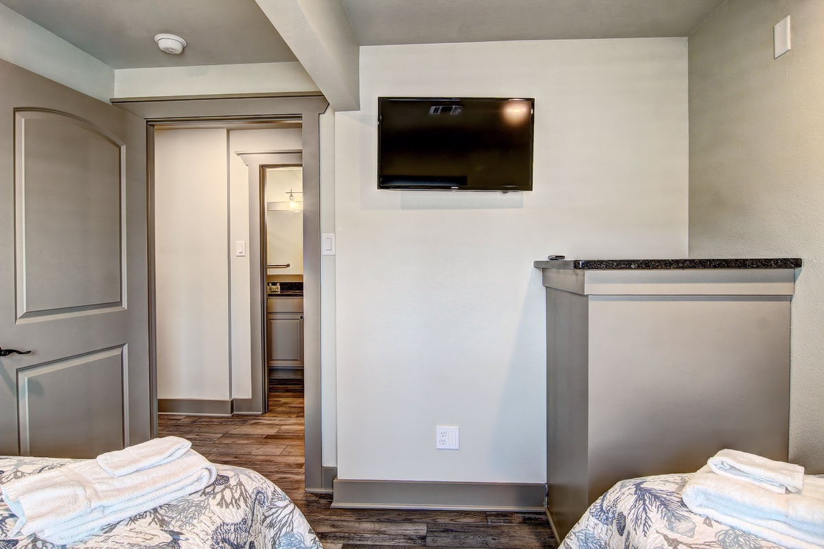 Relax in your modern retreat with twin beds, wall-mounted TV, and sleek kitchenette—perfect for unwinding after exploring.