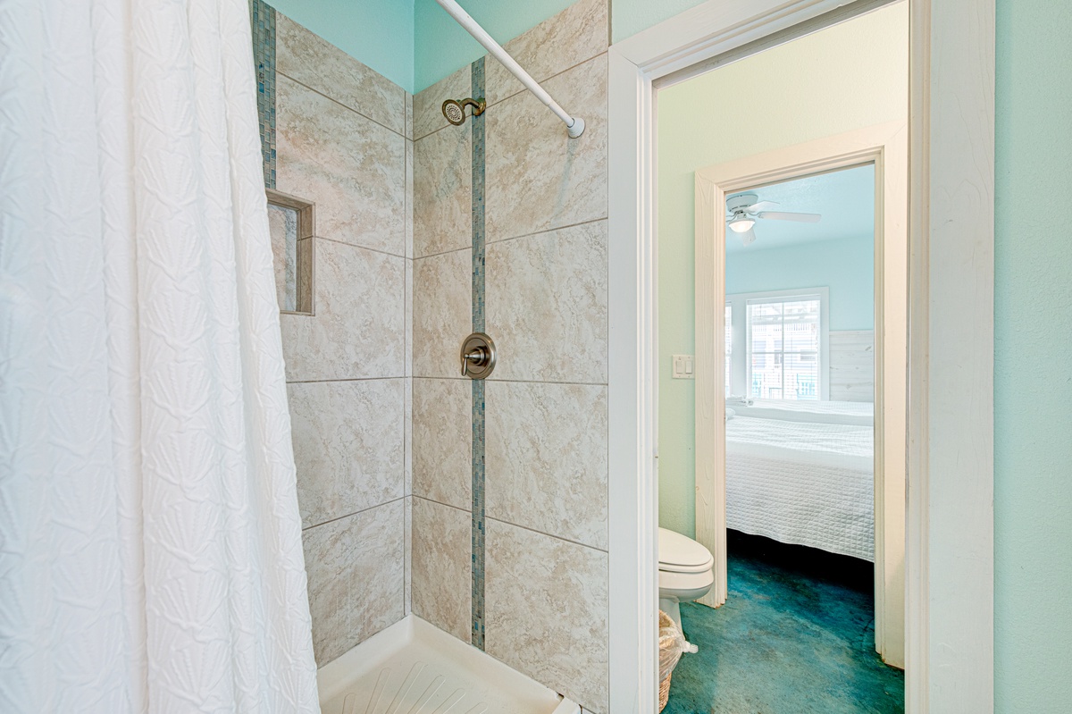 Step into your beautifully tiled shower with elegant stone walls and refreshing aqua accents throughout your private bathroom space.