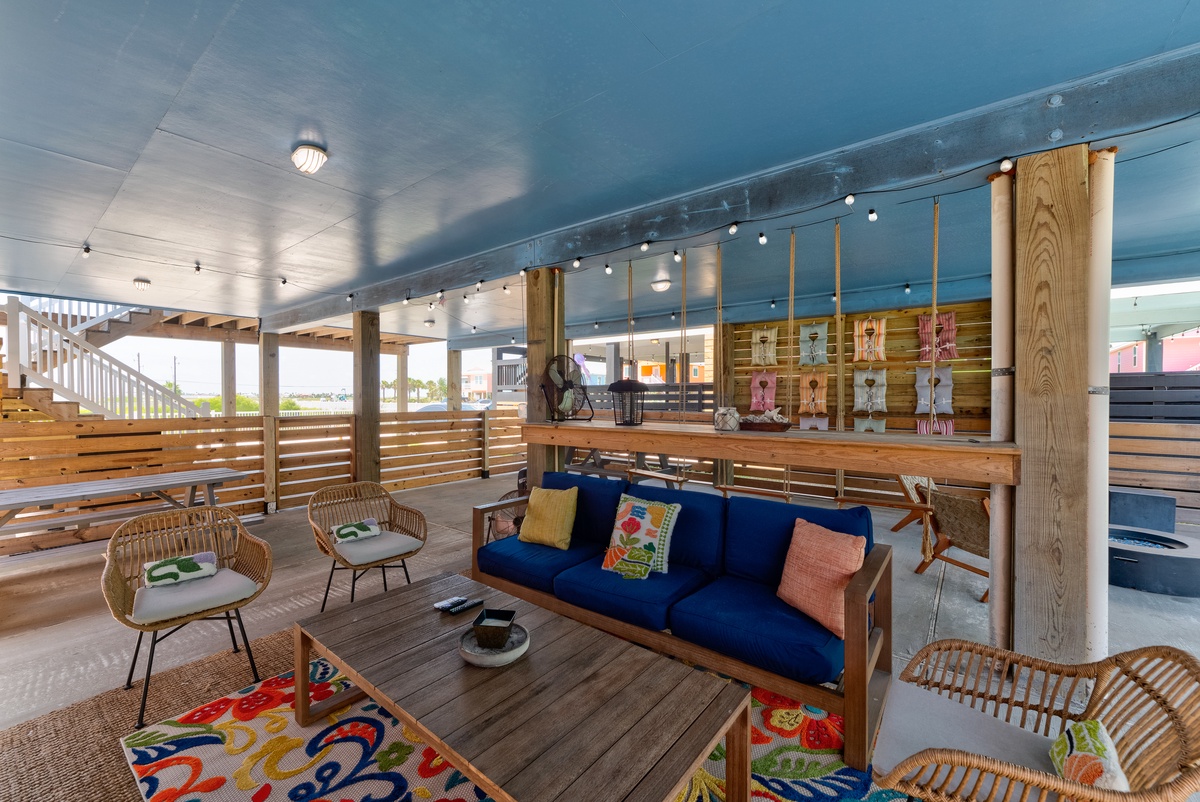 Settle into this breezy covered porch with vibrant blue seating and warm wooden accents—perfect for your morning coffee or evening unwind with glimpses of the outdoors.