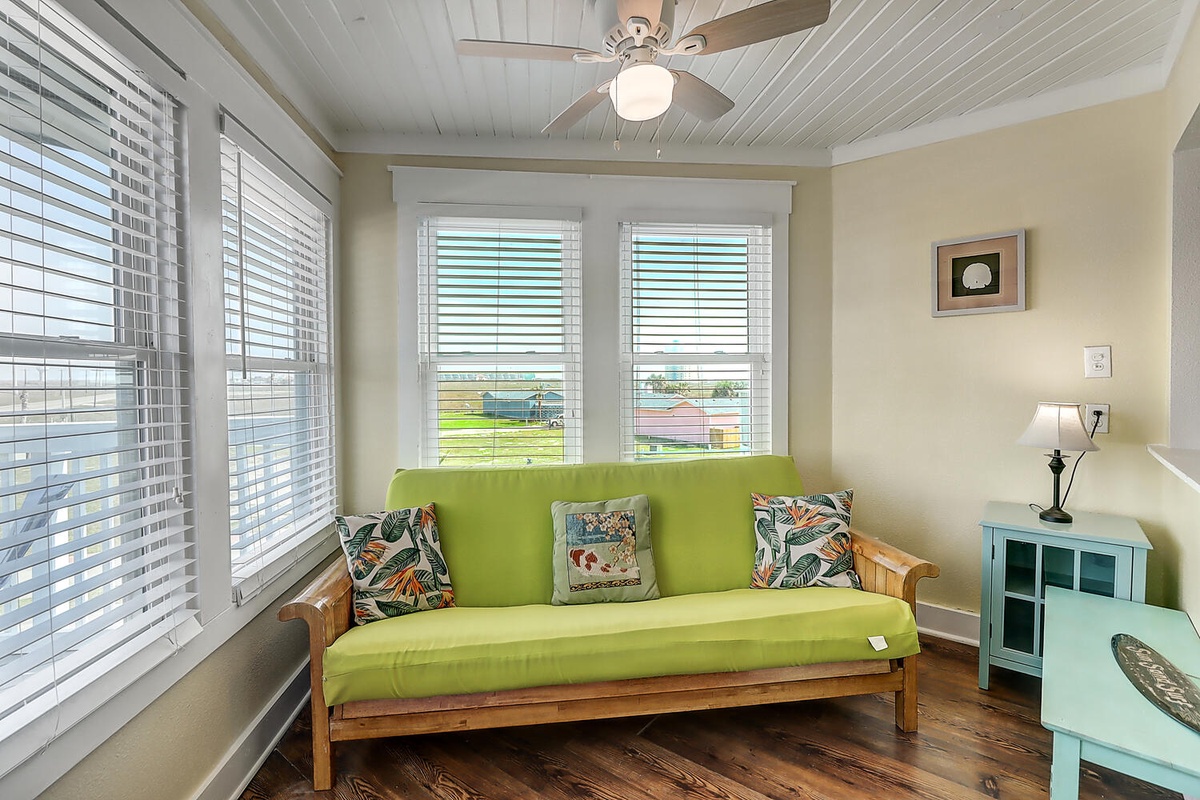 Relax on your bright green sofa surrounded by windows that flood the space with natural light and peaceful views.