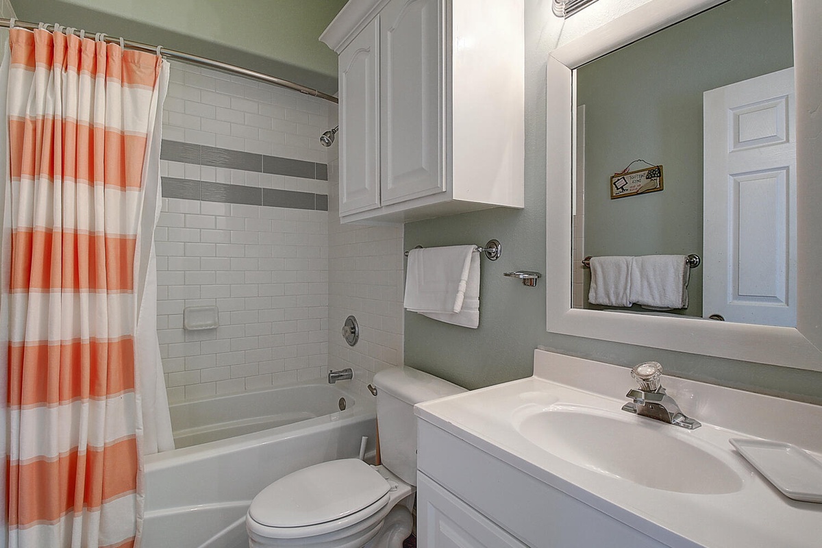 Refresh in your cheerful bathroom with a crisp white tub, modern subway tiles, and playful coral striped curtain adding warmth.