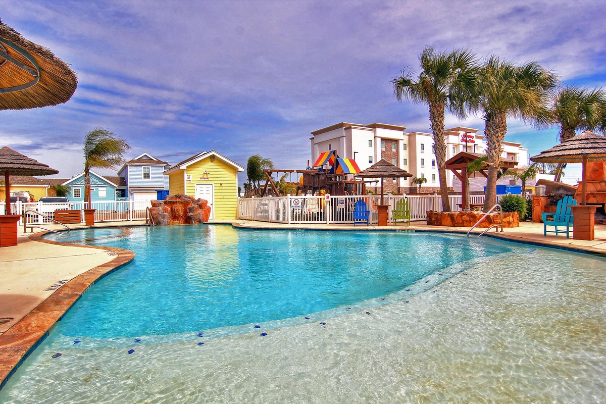 Dive into crystal-clear waters surrounded by tropical palms and colorful beach huts, creating your perfect poolside paradise.