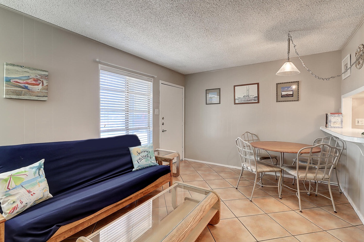 Relax on your cozy futon while enjoying coastal artwork and natural light streaming through the windows in this inviting living space.